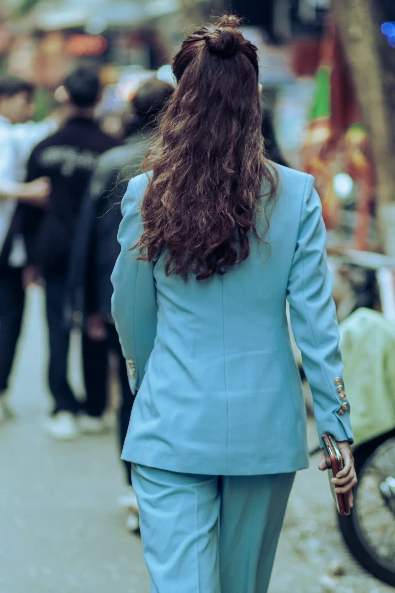 Mulher vista de costas usando conjunto azul-claro em uma rua da cidade