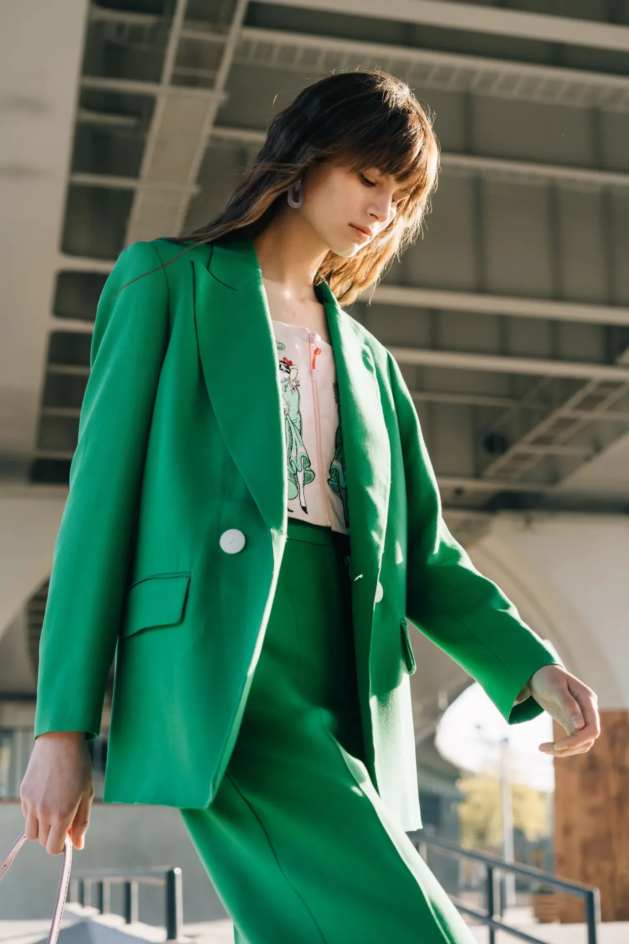 Mulher usa conjunto de alfaiataria verde intenso em ambiente urbano